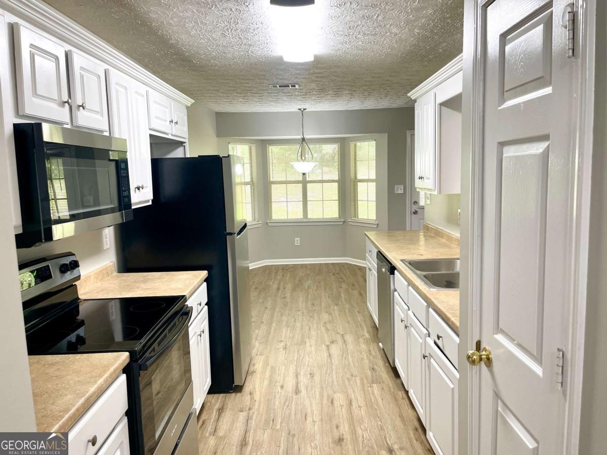 215 Mountain Ridge Covington, GA 30016 - Photo 8 of 23 a kitchen with granite countertop a refrigerator a stove and wooden floor