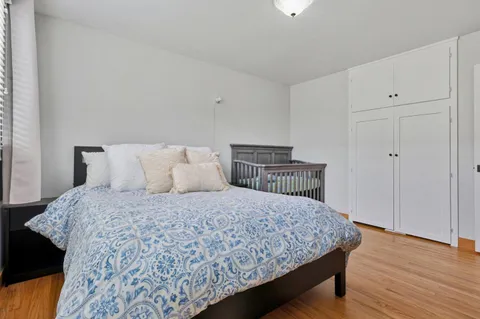 a bedroom with a large bed and wooden floor