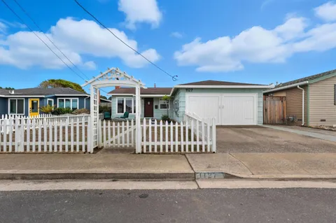 a view of a white house with large windows and a small yard