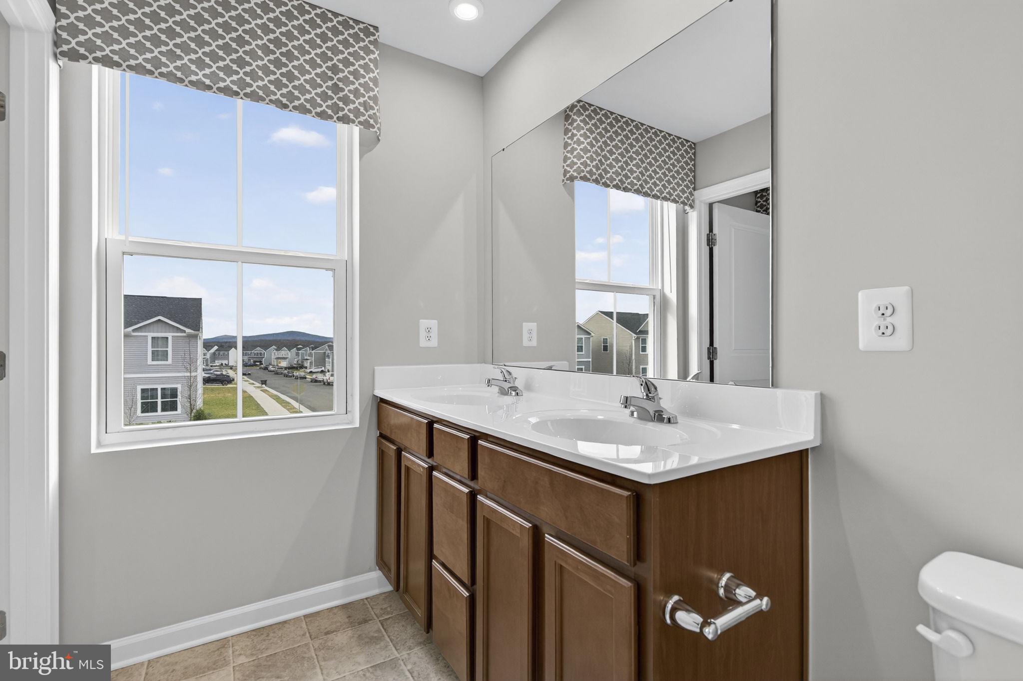 129 Birmingham Drive Middletown, VA 22645 - Photo 45 of 55 a bathroom with a granite countertop sink a toilet a mirror and a window
