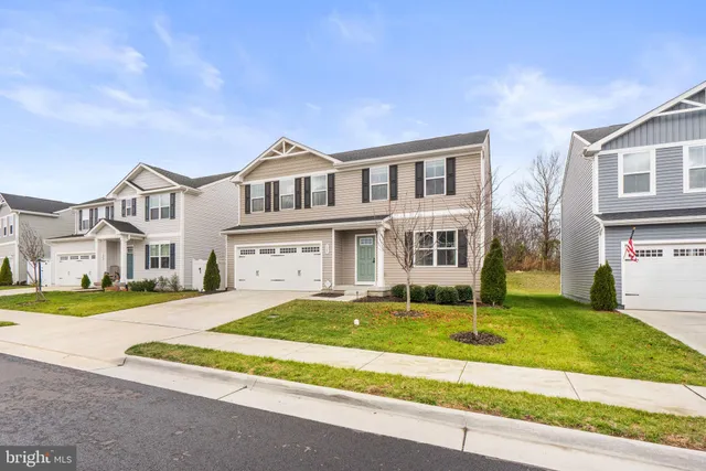a front view of a house with a garden and trees