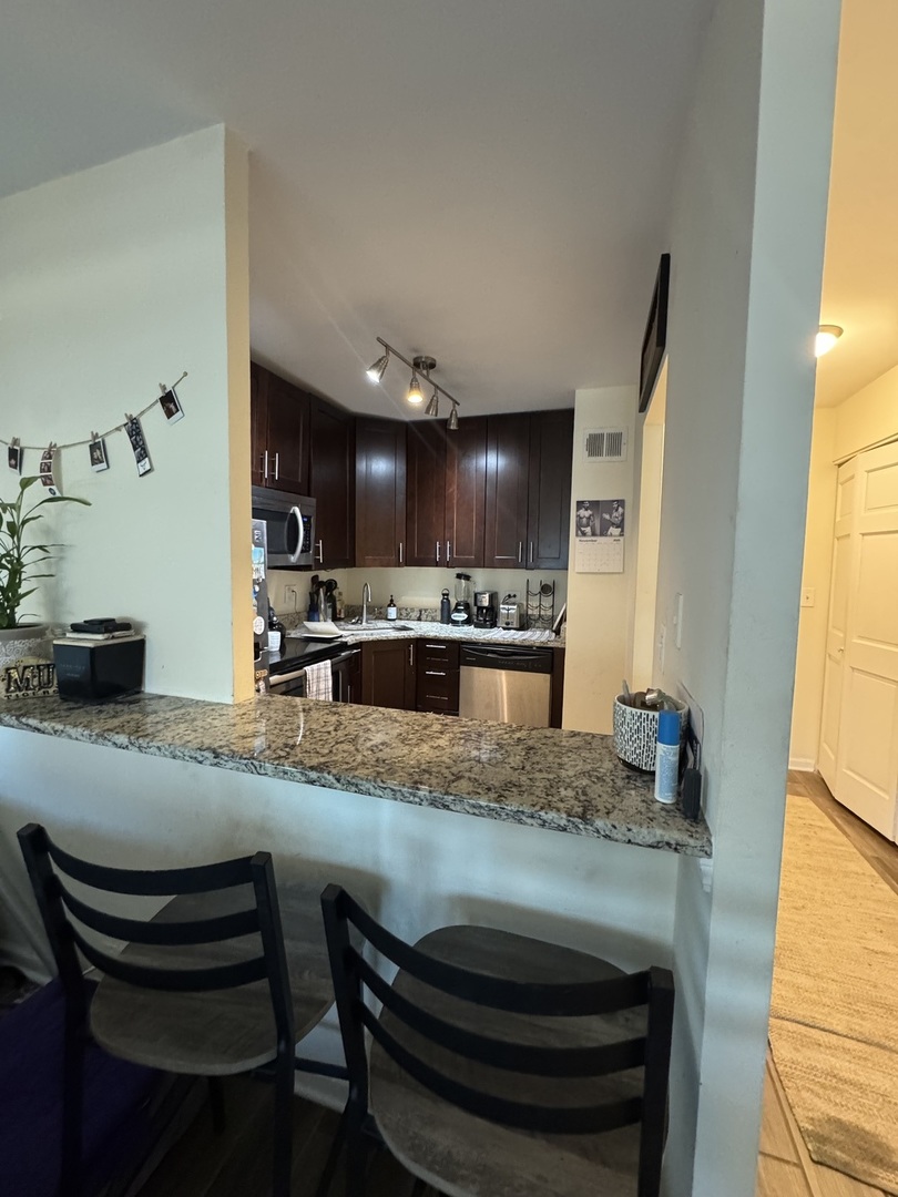 1255 North Sandburg Terrace, Unit 305 Chicago, IL 60610 - Photo 4 of 16 a kitchen with kitchen island a sink stove and wooden floor
