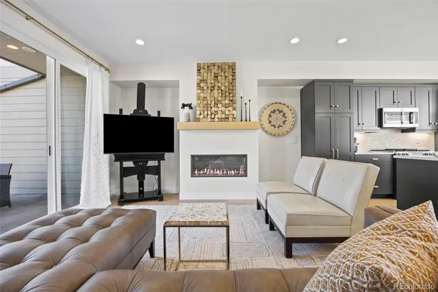 a living room with furniture a flat screen tv and kitchen view