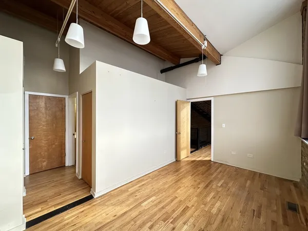 an empty room with wooden floor closet and windows