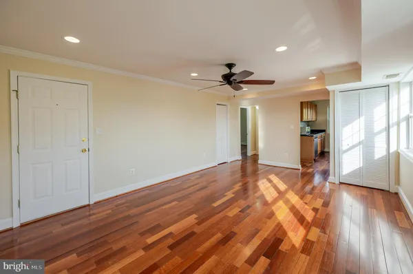a view of empty room with wooden floor and fan