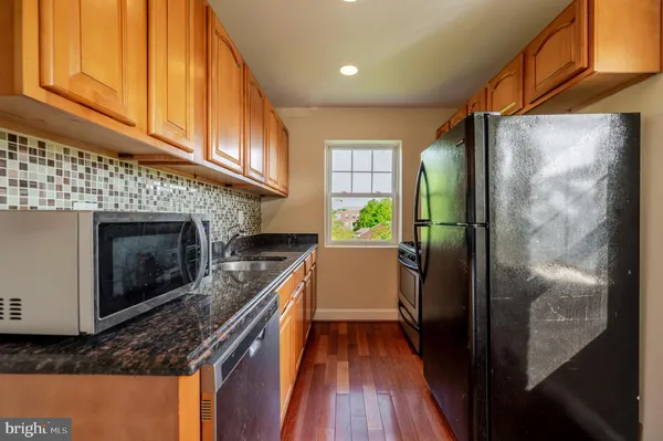 a kitchen with stainless steel appliances granite countertop a refrigerator a stove and a wooden floors