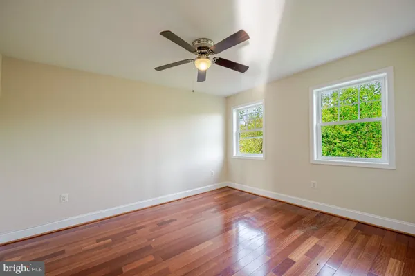 a view of a room with wooden floor and ceiling fan