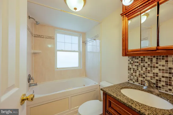 a bathroom with a granite countertop tub sink and mirror with bathtub