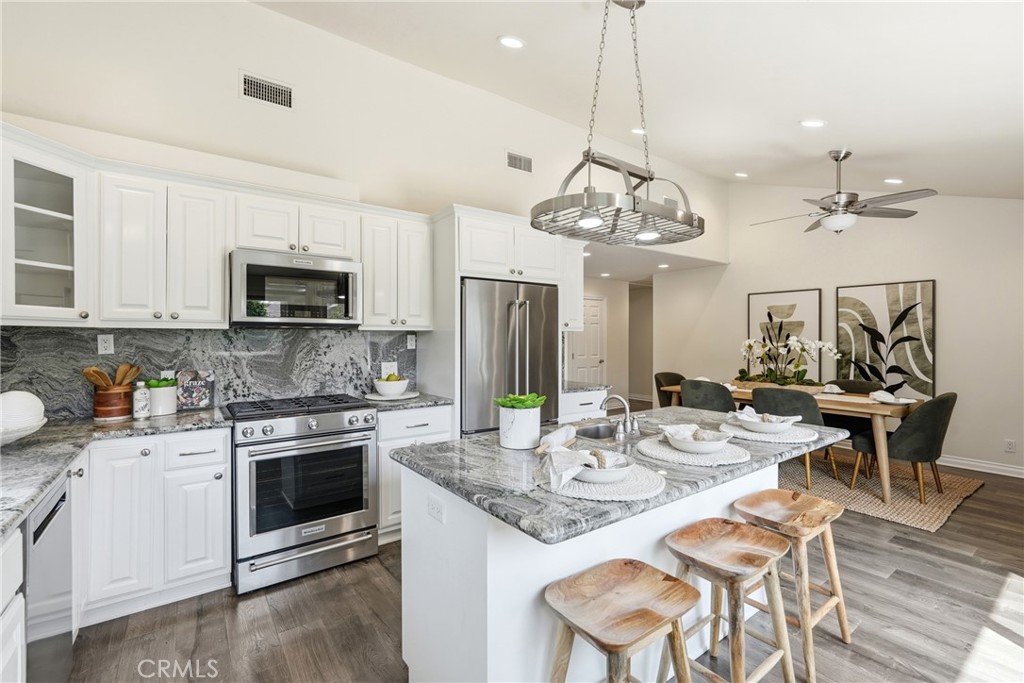 3240 Brace Canyon Road Burbank, CA 91504 - Photo 13 of 39 a kitchen with stainless steel appliances kitchen island granite countertop a stove a sink a dining table and chairs with wooden floor