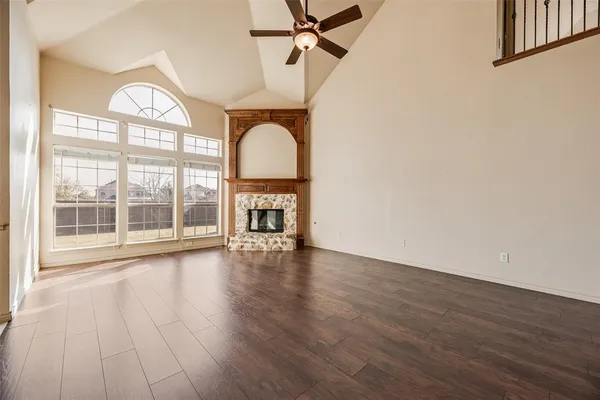 an empty room with wooden floor fan and windows