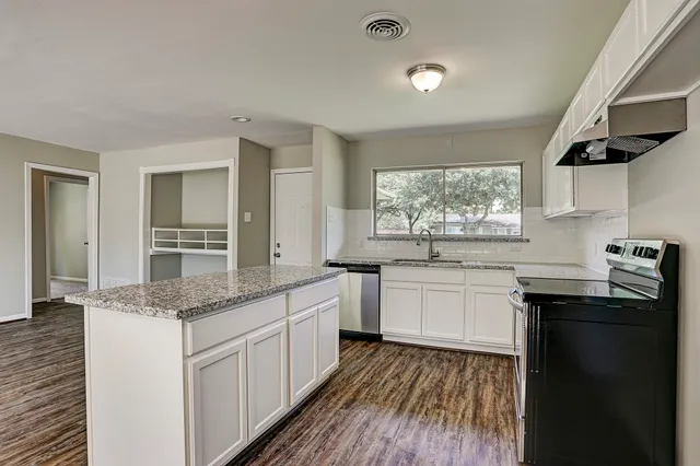 a kitchen with granite countertop sink stove and cabinets