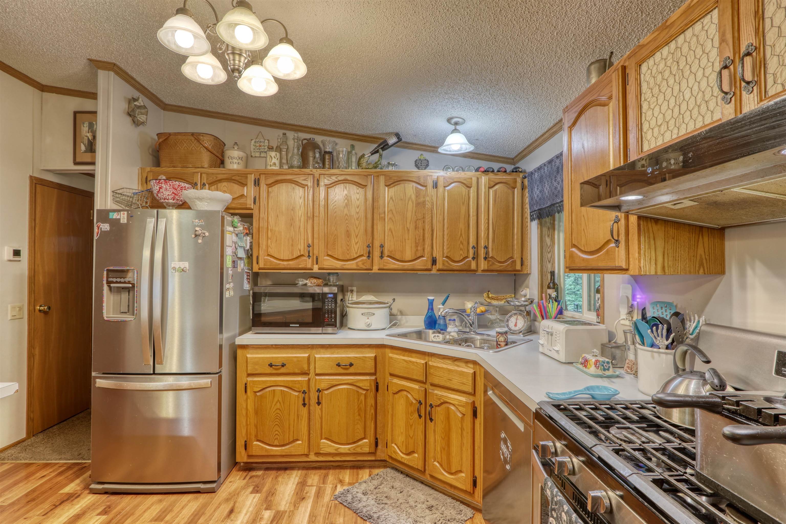48400 Old Grade Road Cable, WI 54821 - Photo 23 of 58 Kitchen featuring a textured ceiling, appliances with stainless steel finishes, ornamental molding, light wood finished floors, and a chandelier