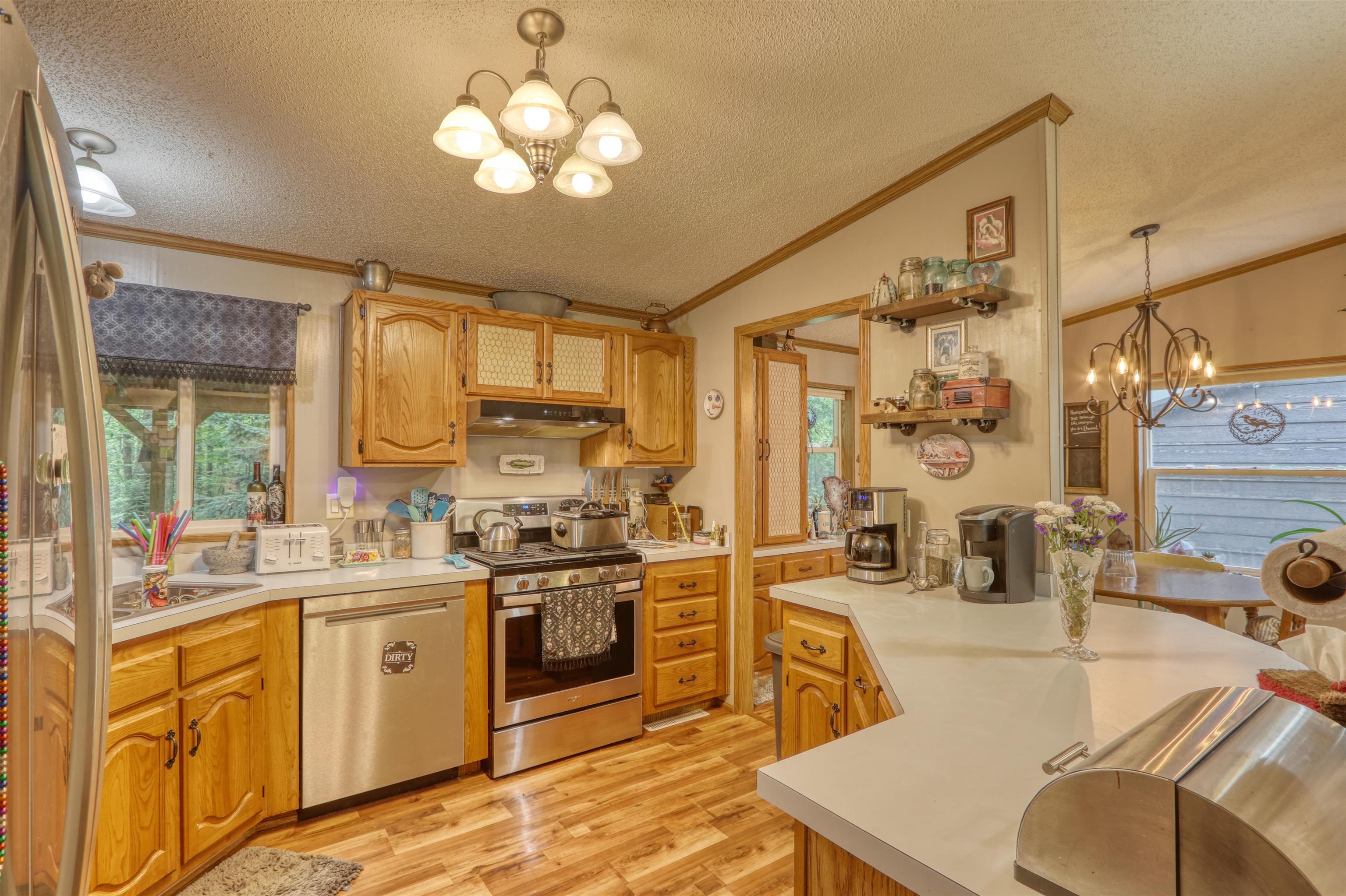 48400 Old Grade Road Cable, WI 54821 - Photo 24 of 58 Kitchen featuring a chandelier, a textured ceiling, appliances with stainless steel finishes, light wood-style flooring, and a peninsula