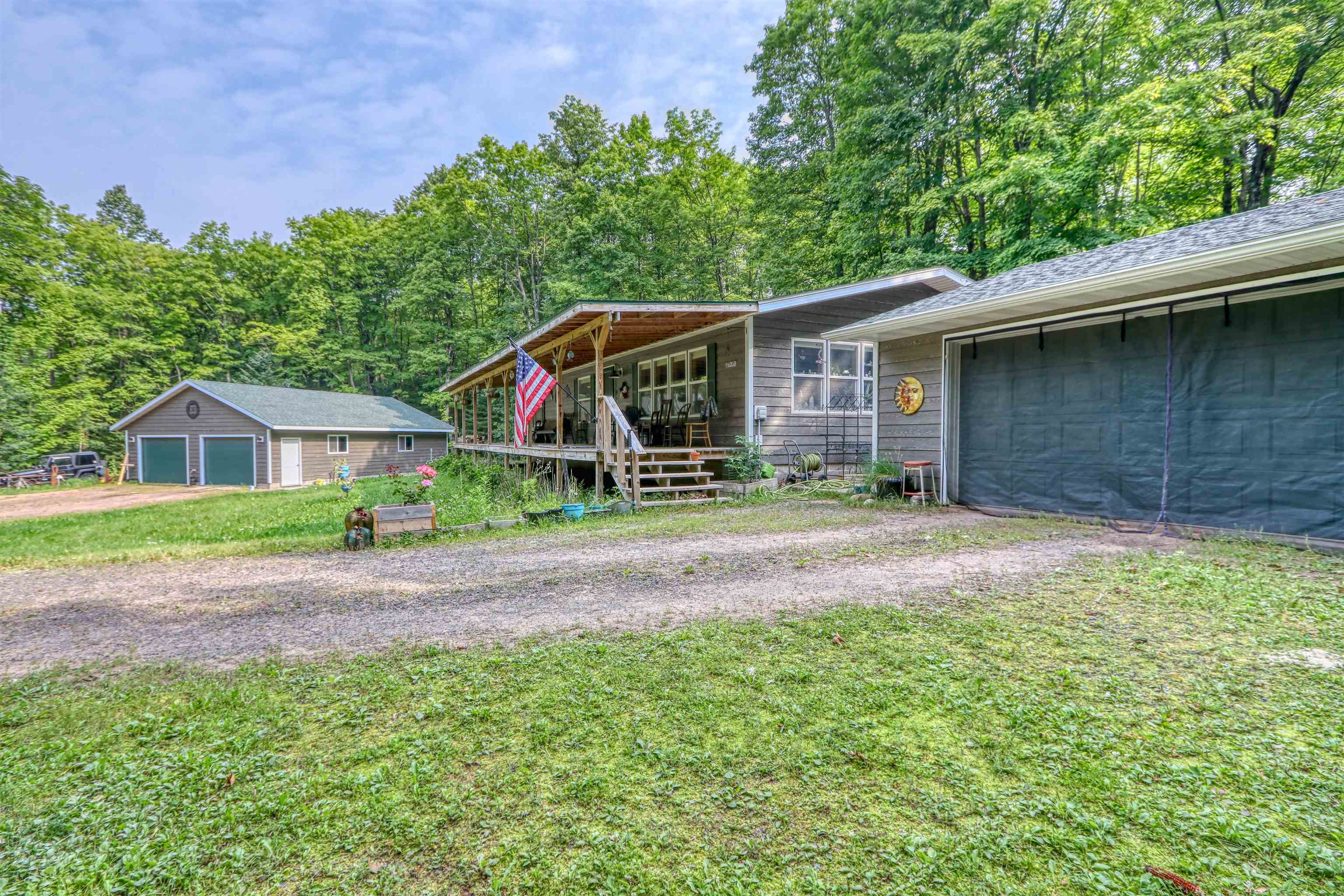 48400 Old Grade Road Cable, WI 54821 - Photo 44 of 58 Ranch-style house with covered porch, an attached garage, a front lawn, dirt driveway, and an outbuilding