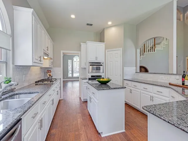 a kitchen with white cabinets sink and stainless steel appliances
