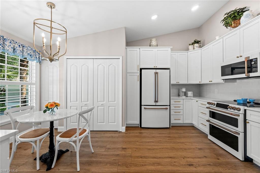 9331 Spring Run Boulevard, Unit 3005 Estero, FL 34135 - Photo 8 of 48 Vaulted ceilings, wood-finish flooring, white cabinetry, integrated stainless steel appliances, and a built-in pantry