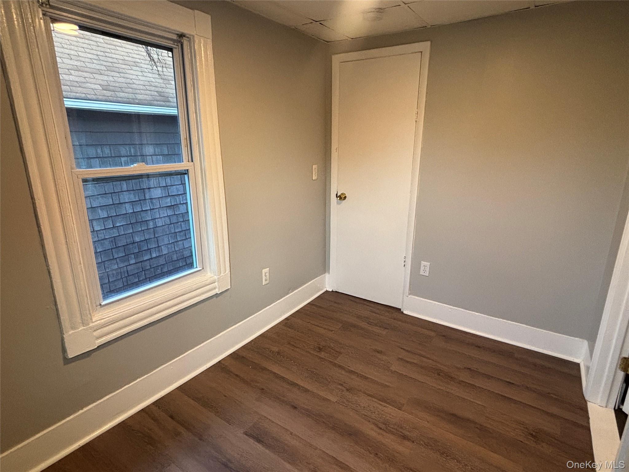 114 Sprague Avenue, Unit 2 Middletown, NY 10940 - Photo 10 of 13 Empty room featuring dark wood-style flooring and a paneled ceiling