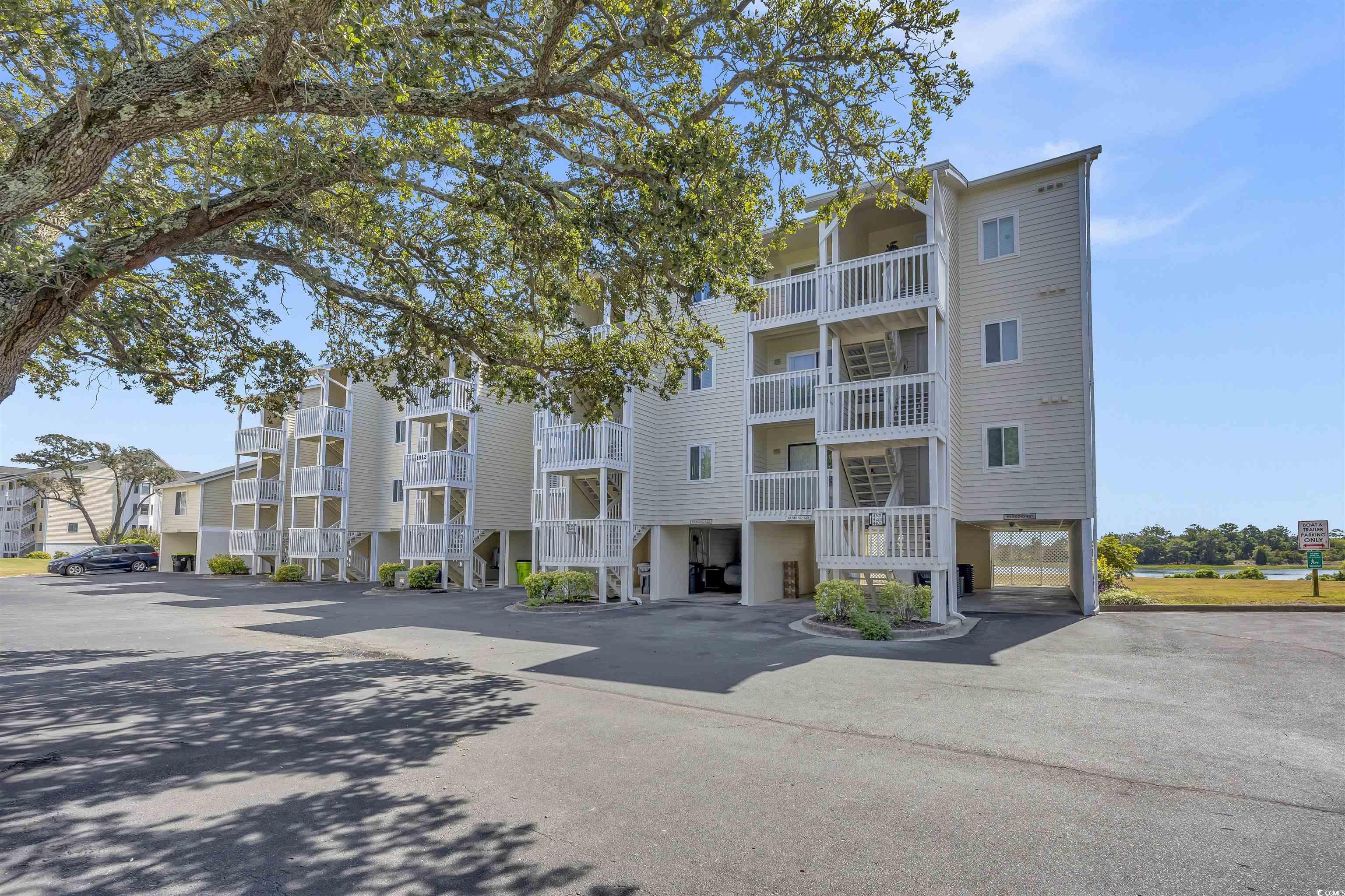 1912 Goose Creek Road Southwest, Unit 4301 Ocean Isle Beach, NC 28469 - Photo 1 of 39 View of apartment building / complex featuring covered and uncovered parking