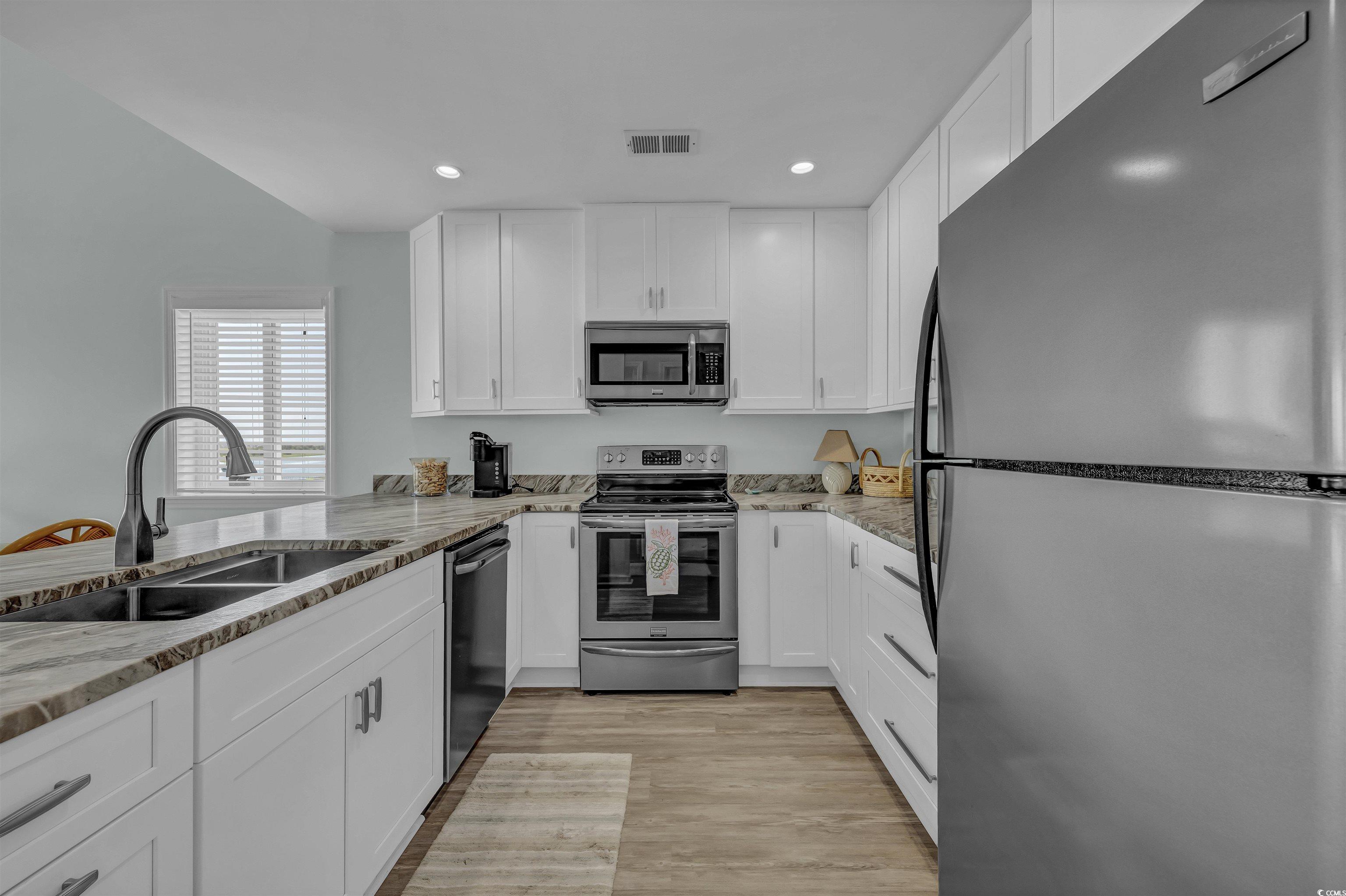 1912 Goose Creek Road Southwest, Unit 4301 Ocean Isle Beach, NC 28469 - Photo 5 of 39 Kitchen with stainless steel appliances, white cabinets, recessed lighting, and light wood-style flooring