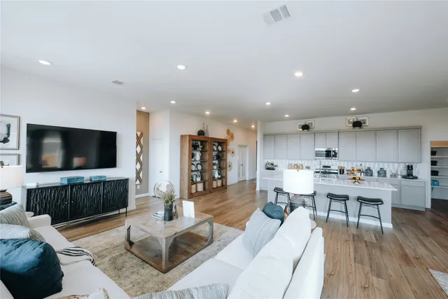 a living room with furniture kitchen view and a large window