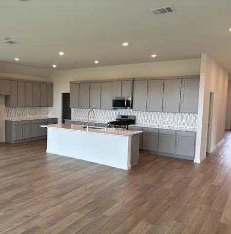 a large kitchen with stainless steel appliances sink a microwave and cabinets