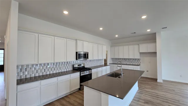 a kitchen with kitchen island granite countertop a sink a counter top space stainless steel appliances and cabinets