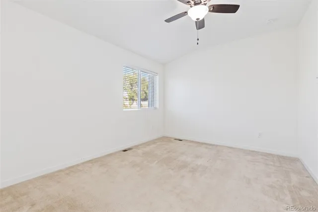 an empty room with a window and a ceiling fan