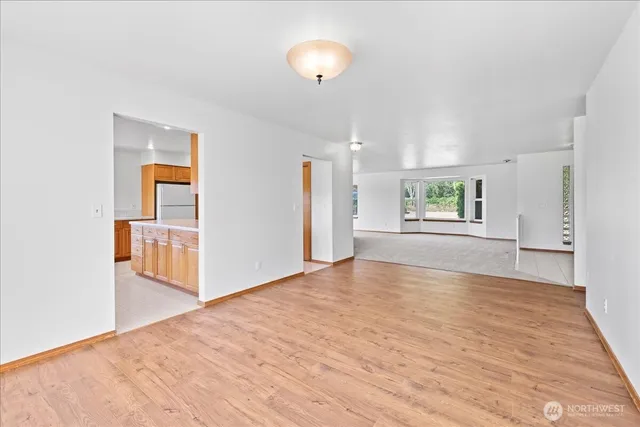 a view of an empty room with window and wooden floor