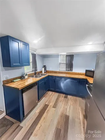 a kitchen with stainless steel appliances granite countertop a sink dishwasher stove and cabinets with wooden floor