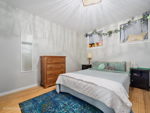 a bedroom with a bed and a dresser with wooden floor