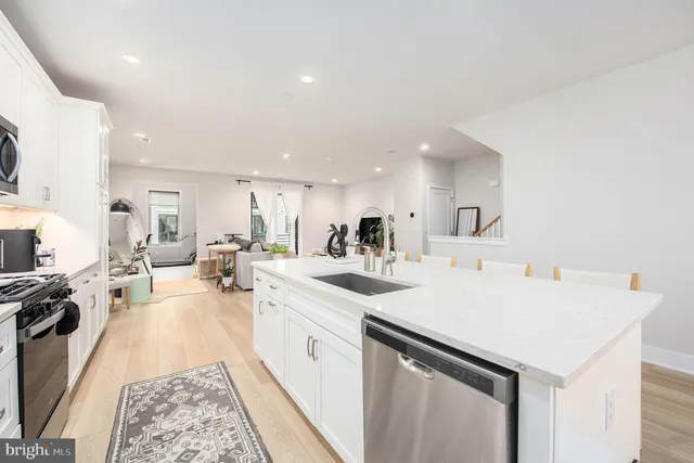 a living room with furniture a chandelier and kitchen view