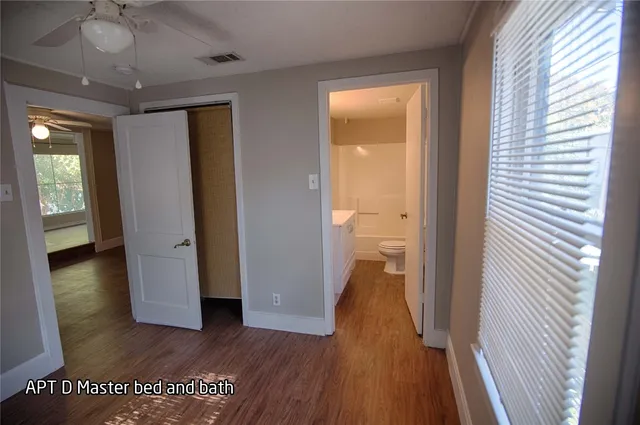 a view of a hallway with wooden floor and a bathroom