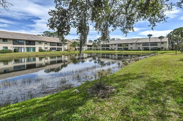 a view of lake with a yard and large trees
