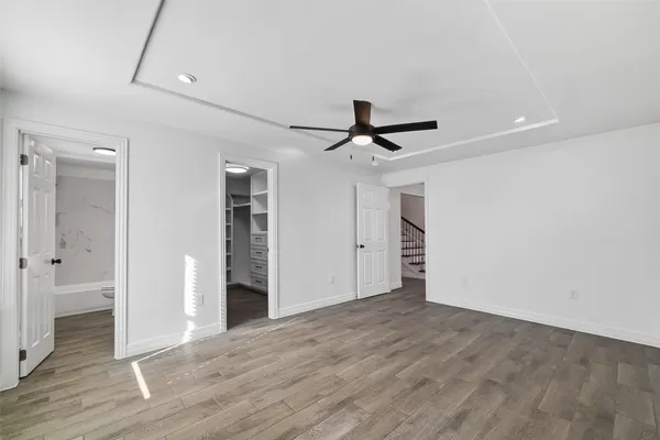 an empty room with wooden floor ceiling fan and windows
