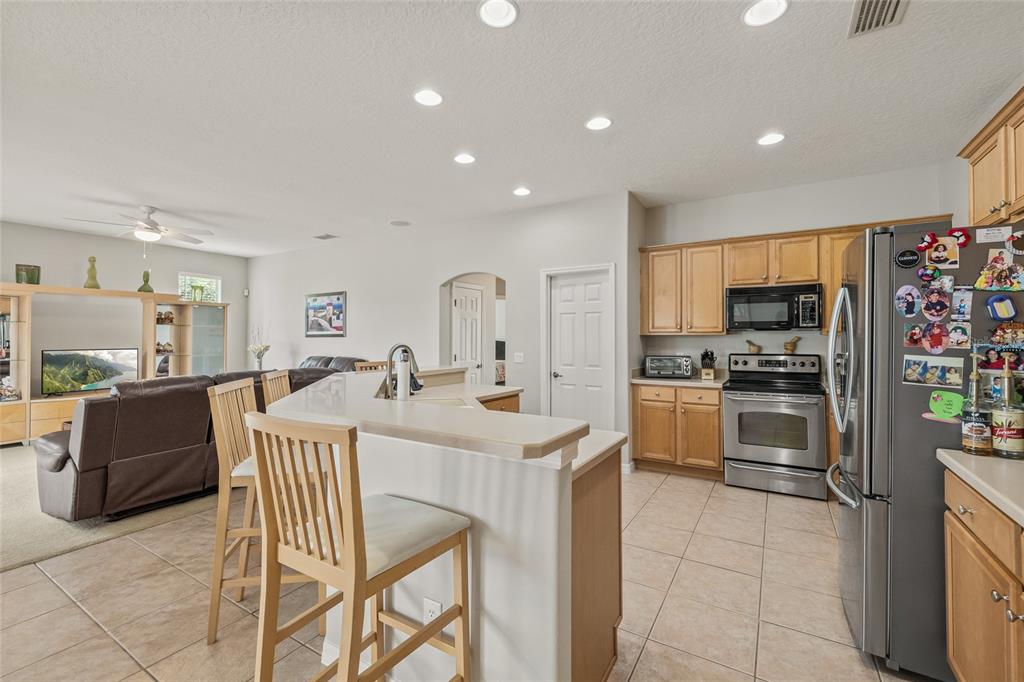 144 Costa Loop Auburndale, FL 33823 - Photo 3 of 34 a kitchen with stainless steel appliances kitchen island granite countertop a stove a sink a microwave a dining table and chairs