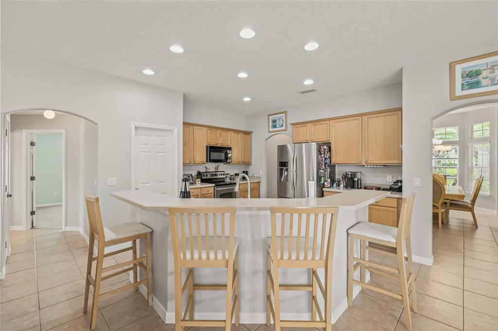 144 Costa Loop Auburndale, FL 33823 - Photo 10 of 34 a kitchen with stainless steel appliances kitchen island granite countertop a refrigerator a stove a dining table and chairs with wooden floor
