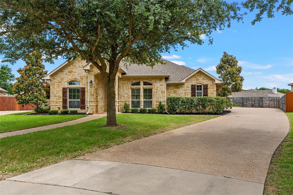 144 Ellis Farm Road Hewitt, TX 76643 - Photo 4 of 36 Stone facade home featuring a large mature tree, a concrete pathway, a gravel driveway, and manicured shrubbery