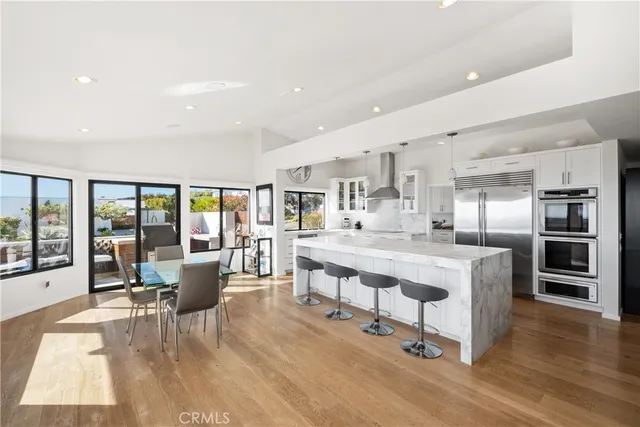 a large white kitchen with a large window and stainless steel appliances