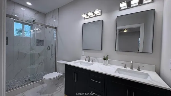 a bathroom with a double vanity sink toilet and shower