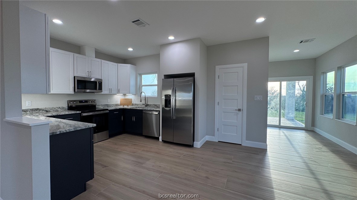 3917 Harbor Bolton Road Franklin, TX 77856 - Photo 18 of 26 a kitchen with granite countertop a refrigerator a sink a stove top oven and wooden floor