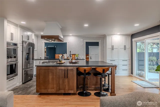 a kitchen with stainless steel appliances granite countertop a table chairs sink refrigerator and cabinets