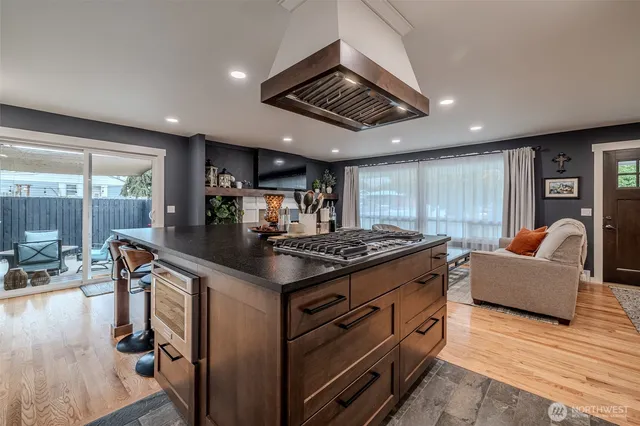 a kitchen with stainless steel appliances granite countertop a stove and a view of living room