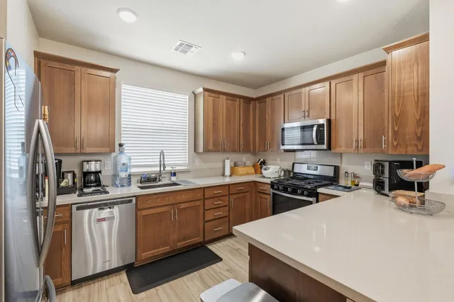 a kitchen with stainless steel appliances a sink a stove a refrigerator cabinets and a window
