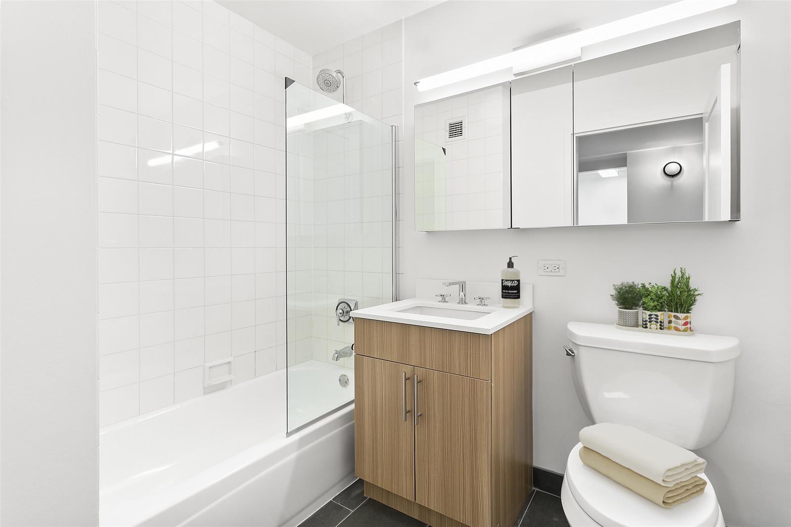 200 East 87th Street, Unit 17F Manhattan, NY 10028 - Photo 4 of 9 a bathroom with a sink a toilet and shower