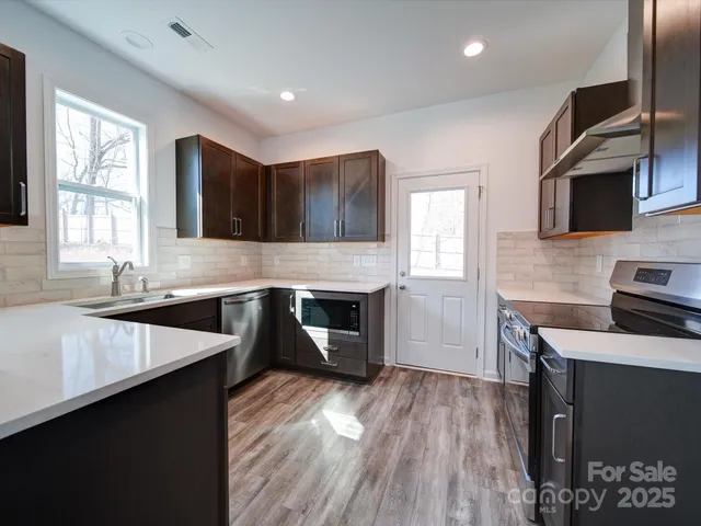 a kitchen with stainless steel appliances granite countertop a sink stove and microwave