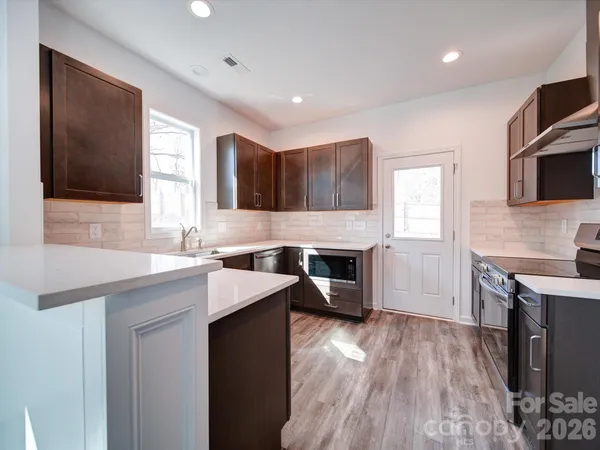 a kitchen with a sink dishwasher a stove and a refrigerator with wooden floor