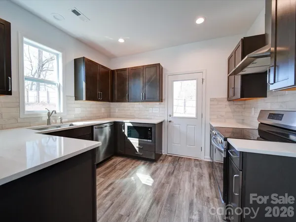 a kitchen with granite countertop a sink wooden floor and stainless steel appliances