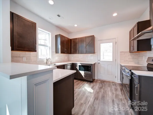 a kitchen with granite countertop a stove top oven a sink dishwasher and a fireplace with wooden floor