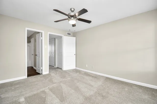 an empty room with ceiling fan and window