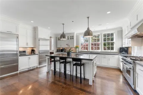 a kitchen with kitchen island a counter top space a sink stainless steel appliances and cabinets